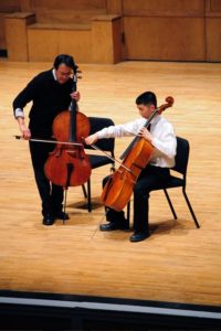 Image of Yo Yo Ma with a student, both playing cellos on stage.