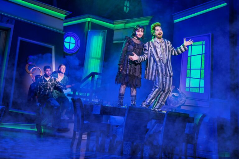 Photo from Beetlejuice of Lydia and Beetlejuice standing on a table.