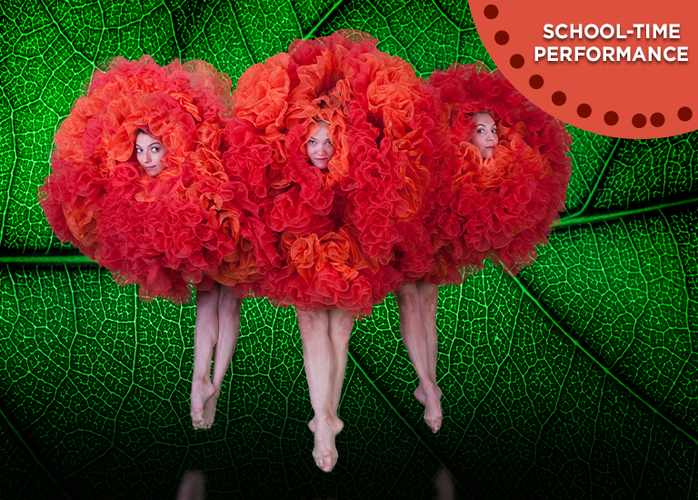 Image of 3 dancers in red flower costumes, dancing in front of a green leaf backdrop