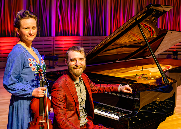 Photo of Katie McNally holding a violin and Neil Pearlman sitting at a piano