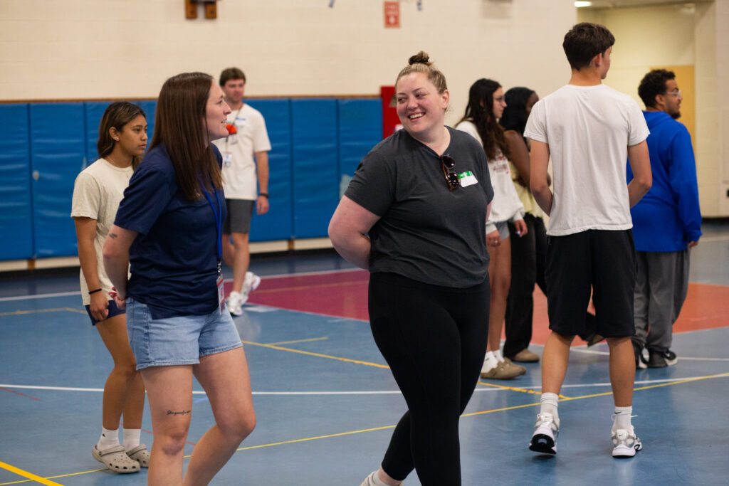 Photo of two people smiling at each other while walking through a gym