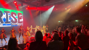 Photo of Ndlovu Youth Choir singing on stage under bright stage lights at the Edinburgh Fringe Festival